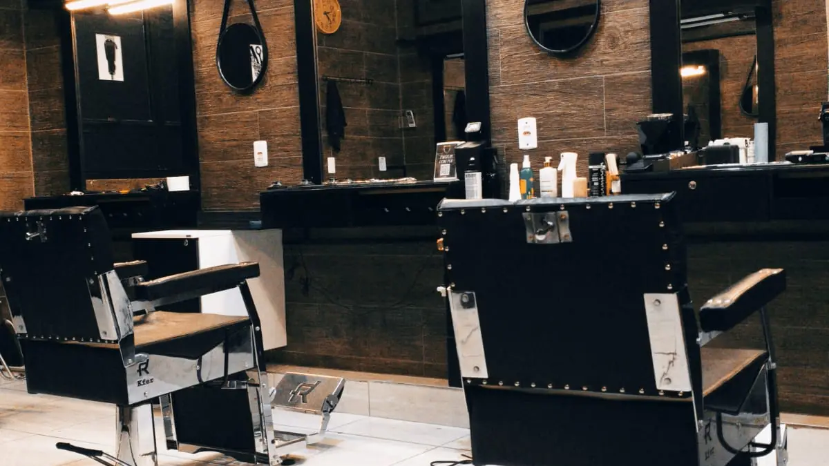 Interior da Dom Mark Barbearia: cadeiras clássicas de couro, espelhos redondos e quadros na parede